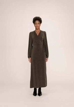 Robe enveloppante longue et scintillante de couleur noire avec un décolleté en V, des manches longues volumineuses et une ceinture à la taille, associée à des escarpins noirs à bout pointu.