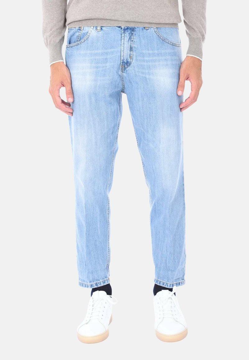 Jeans in denim azzurro chiaro con una vestibilità dritta e texture sbiadita, abbinati a sneakers bianche e a un maglione grigio.