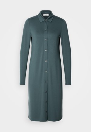 Rochie cu mâneci lungi și nasturi, de culoare teal estompată. Fabricată dintr-un material fin, cu guler și slituri pe laturile tivului.