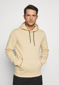 Beige capuchon sweatshirt van zachte stof, met een kangoeroezak, zwarte koordjes en ribgebreide manchetten en zoom.