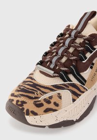 Sneaker chunky con stampa leopardata e tigre, mesh beige, lacci marroni con strisce riflettenti e etichetta in metallo del marchio, primo piano sull'area delle punte.