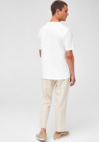 T-shirt en coton blanc, pantalon rayé crème et baskets beiges. Design simple avec des manches courtes et un col rond.