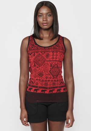 Rotes Tanktop mit aufwendigen schwarzen Mustern und Tiermotiven. Schwarzer Saum um den Hals- und Armöffnungen. Kombiniert mit schwarzen Shorts.