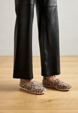 Leopard print instappers hebben een zachte stoffen bovenkant, een ronde neus en een slipvaste zool, gecombineerd met zwarte leren wijde broekspijpen.