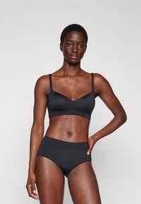 Black seamless bra with adjustable straps and a v-neck design, paired with matching high-waisted briefs, both made from a smooth fabric.