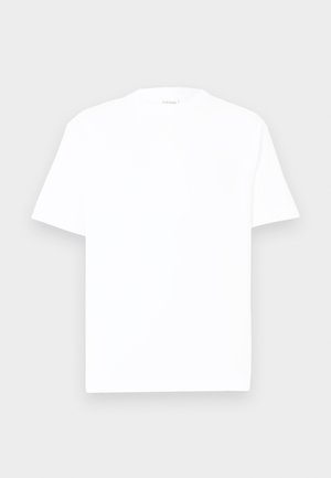 Camiseta de algodón blanca con cuello redondo, mangas cortas y corte relajado. Textura suave, detalles mínimos, sin patrones ni gráficos.