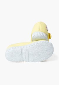 Scarpa di tela gialla con suola in gomma bianca. Presenta una punta rotonda, una parte superiore testurizzata e un'etichetta sul lato. Perfetta per un abbigliamento casual.