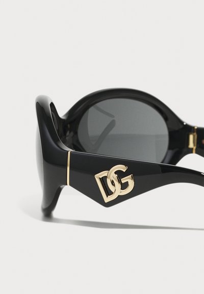 Occhiali da sole neri con finitura lucida, lenti scure rotonde, dettagli in oro e un logo "DG" intrecciato di grande impatto sulle stanghette.