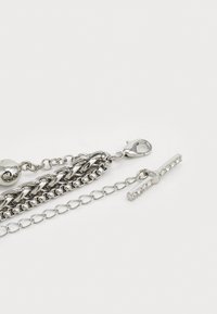 Bracelet en chaîne en argent comprenant un mélange de maillons lisses et texturés, un fermoir à homard et une barre avec de petits cristaux incrustés.