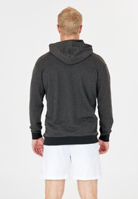 Sudadera gris oscuro con una tela texturizada, mangas largas y capucha trasera. Presenta puños y cintura acanalados, vista desde la parte posterior.