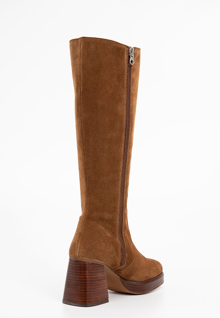 Botte en suède marron, hauteur genou, avec une fermeture éclair sur le côté et un épais talon en bois empilé.