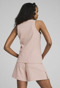 Top in tessuto rosa chiaro con una vestibilità comoda, abbinato a pantaloni corti coordinati con tasca e spacchi laterali per facilitare i movimenti.