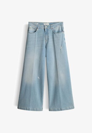 Lichtblauwe wijduitlopende spijkerbroek met lichte slijtage aan de linker dij en rechterknie, voorzakken en knoopsluiting.