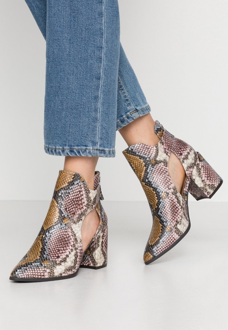 Botines de tacón alto con diseño de serpiente multicolor. Presentan recortes, punta puntiaguda y un tacón grueso y resistente.