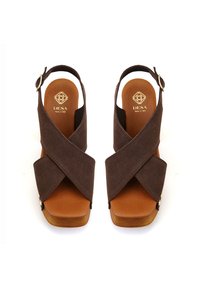 Braune Wildleder-Wedge-Sandalen mit überkreuzten Riemen, einem hellbraunen Fußbett und einer goldenen Schnalle. Sie zeichnen sich durch eine glatte Textur und ein schlichtes, modernes Design aus.