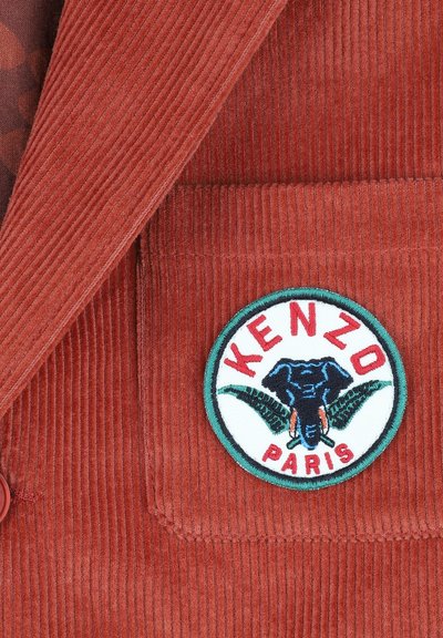 Veste en velours côtelé couleur rouille avec un patch brodé circulaire mettant en avant un graphique d'éléphant et le texte "KENZO PARIS".