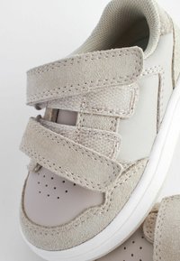 Helle graue Sneaker mit Klettverschluss, ausgestattet mit einer glatten Lederkappe und einem weichen Wildleder-Obermaterial, runder Form und perforiertem Design.