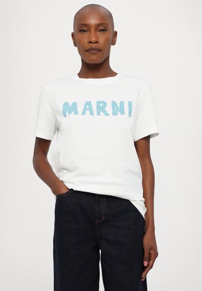 Valge puuvillane t-särk, millel on sinine pintslijoonega kiri "MARNI." Lühikesed varrukad ja ümar kaelus, koos tume-denim pükstega.