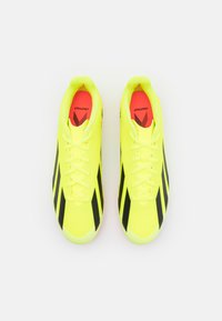 Botas de fútbol amarillas brillantes con rayas negras, que cuentan con un diseño elegante, parte superior texturizada y cierre con cordones, para un rendimiento óptimo.