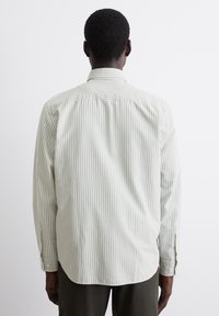 Light green striped long-sleeve shirt with a relaxed fit, button cuffs, and a straight hem. Soft fabric texture with visible seam detailing.