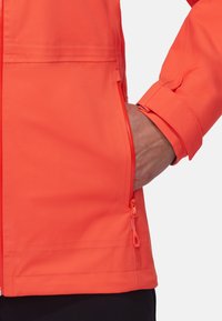 Veste imperméable orange vif avec fermeture éclair et détails de poches latérales, dotée d'un poignet ajusté et d'une texture lisse.