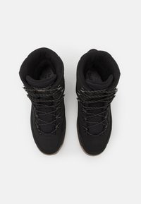 Schwarze High-Top-Stiefel aus strukturiertem Stoff, mit verstärkter Zehenkappe und elastischen Schnürsenkeln. Gummiaußensohle sorgt für Haftung; weiche Innenauskleidung für Komfort.
