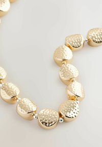 Collier doré avec des perles en métal texturées et rondes, présentant des surfaces alternées lisses et martelées, séparées par de petits entretoises métalliques.