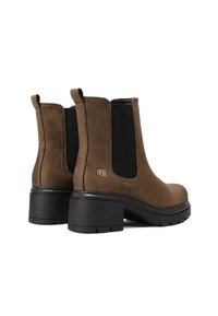 Stivaletti ankle in suede marrone con pannelli elastici laterali, dettagli neri testurizzati e tacco spesso nero. Branding discreto sul lato esterno.