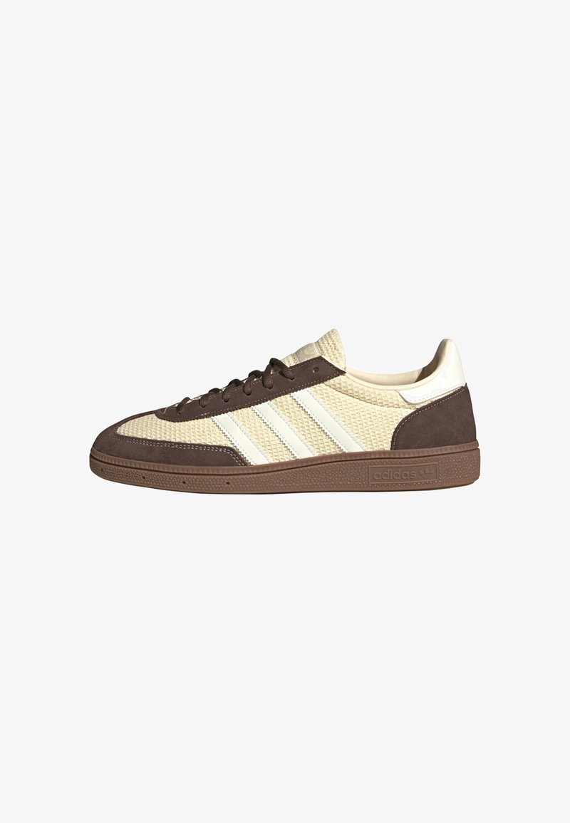 Χαμηλού τύπου αθλητικό παπούτσι Adidas σε μπεζ υφαντό ύφασμα με καφέ σουέντ επικάλυψη, λευκές ρίγες και καφέ καουτσούκ σόλα.