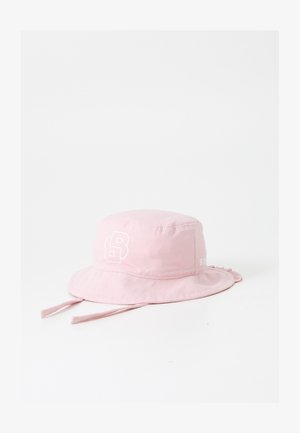 Vaaleanpunainen bucket-hattu, joka on valmistettu pehmeästä kankaasta, ja jossa on valkoinen logo sekä nyörikoristeet. Hattuun kuuluu leveä, litteä lippa auringon suojaksi.