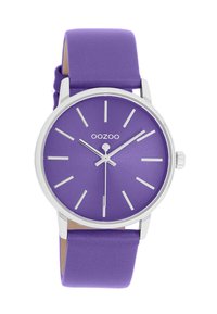 Purple watch with a matte dial, silver accents, simple hour markers, and a smooth purple silicone strap. Overall round shape.