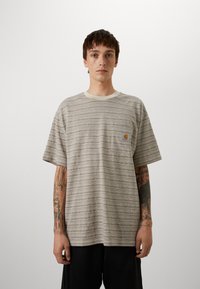 Striped short-sleeve t-shirt in beige and cream, featuring a pocket and a logo label. The fabric has a textured appearance.