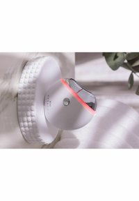 Stylpro-enhet med en vit, rund bas och kromöverdel. Har en mjuk röd ljusring och en texturerad cirkulär bas.