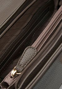 Bruine gestructureerde leren tasinterieur met meerdere compartimenten, ritsafsluitingen en een zachte voering met een diamanten patroon.