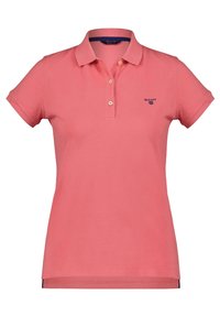 Růžové polo tričko vyrobené z bavlny, s klasickým límečkem, krátkými rukávy a třemi knoflíky u krku. Logo GANT v námořnické modři.
