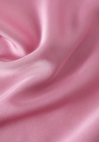 Tejido de satén rosa suave con una textura lisa y brillante, que muestra pliegues y curvas suaves, enfatizando su caída fluida y su delicado brillo.