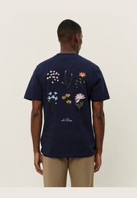 Tricou din bumbac de culoare bleu marin, cu broderie florală colorată pe spate, având diverse modele de flori și accente verzi.