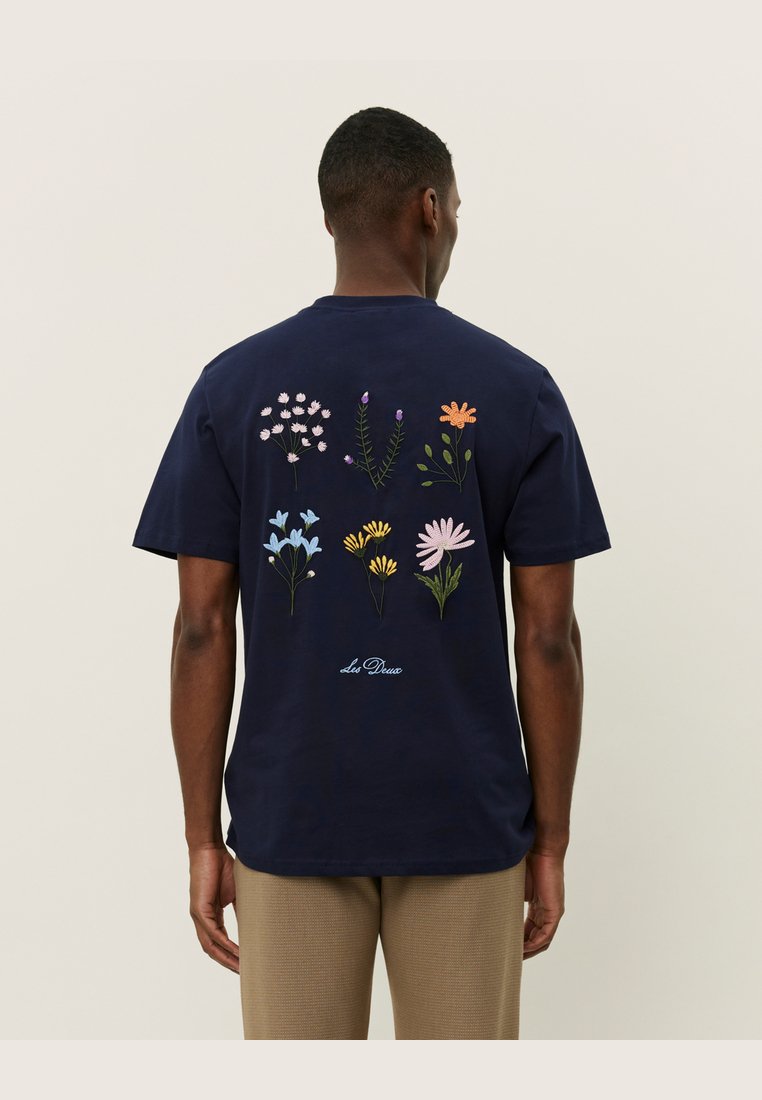 Tricou din bumbac de culoare bleu marin, cu broderie florală colorată pe spate, având diverse modele de flori și accente verzi.