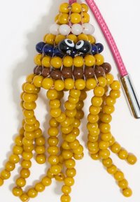 Yellow beaded octopus keychain with a pink strap. Features black and white eyes, brown accents, and long, dangling yellow legs.