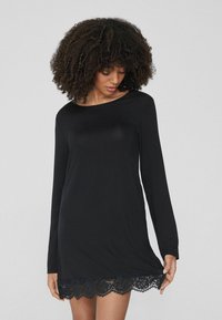 Abito lungo nero a maniche lunghe realizzato in un materiale morbido, con orlo in pizzo. Design semplice con scollatura rotonda e vestibilità comoda.