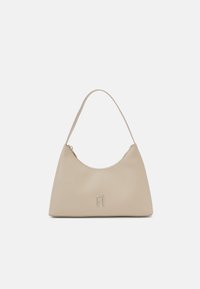 Beżowa torebka na ramię wykonana z gładkiego materiału, o zaokrąglonym kształcie, z zamkiem błyskawicznym i złotym wytłoczonym logo na przodzie.