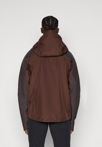 Een bruin en donkergrijze jas met een capuchon, met een gladde, licht glanzende textuur en een gestroomlijnd ontwerp. Geen zichtbare hardware of accenten.