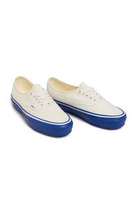 Canvas sneakers, crèmekleurig bovenwerk met blauwe rubberen zool, witte veters, contrasterende blauwe streep, ronde neus en laag profiel.