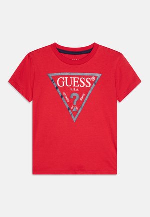 T-shirt rossa in cotone con una grafica triangolare grigia e la scritta "GUESS U.S.A." e "? 1981", maniche corte e scollo rotondo.