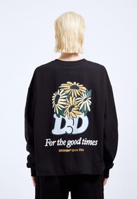 Black long-sleeve sweatshirt featuring a large floral graphic in yellow and green on the back, with the text "For the good times" and "DD."