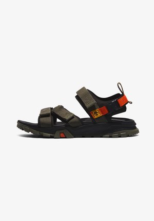 Dark green and black hiking sandals with adjustable straps, textured fabric, and a rugged sole featuring orange accents and a logo patch.
