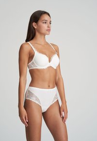 Set di lingerie in pizzo bianco, composto da un reggiseno imbottito con bordi ondulati e completato da uno slip a vita alta con dettagli in pizzo floreale.