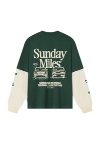 Tmavě zelená a krémová košile s dlouhým rukávem s náčrty vintage aut a nápisy "Sunday Miles" a "Spojujeme svět skrze klasickou kulturu."