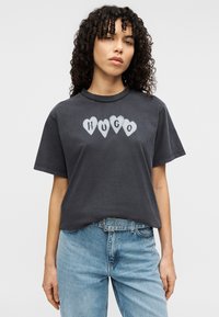 Κοντομάνικο μπλουζάκι ανθρακί γκρι με εκτύπωση τεσσάρων καρδιών με τη λέξη "HUGO" στο κέντρο. Κανονική εφαρμογή με στρογγυλή λαιμόκοψη.