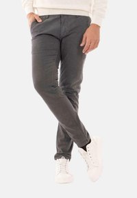 Pantaloni slim-fit grigi in tessuto misto cotone con tasche frontali e dettagli di cucitura sottili, abbinati a sneakers bianche.